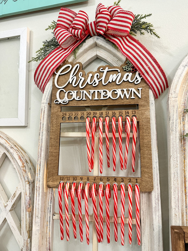 Christmas countdown calendar with candy canes and a large red and white bow on a decorative wall.