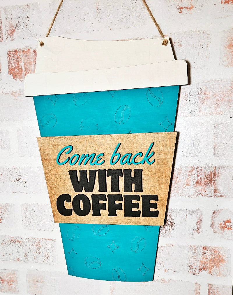 Decorative sign shaped like a coffee cup with 'Come back with coffee' text on a textured wall.