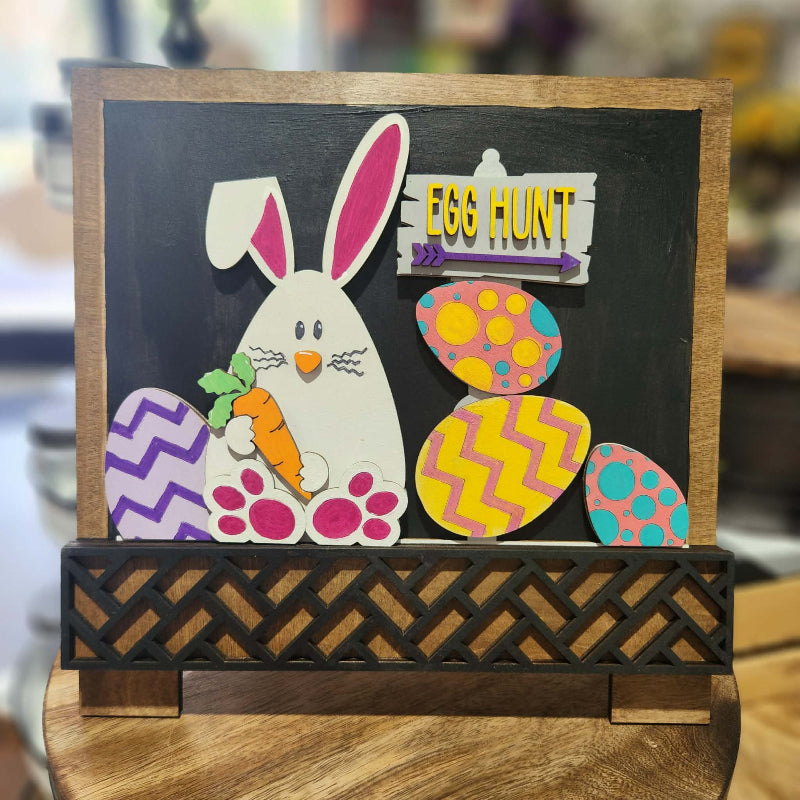 Decorative sign with a bunny and Easter eggs on a blackboard background, featuring the text 'Egg Hunt'.