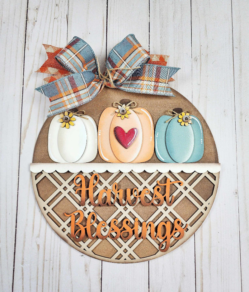 round wooden door hanger with 3 pumpkins and the word Harvest Blessings