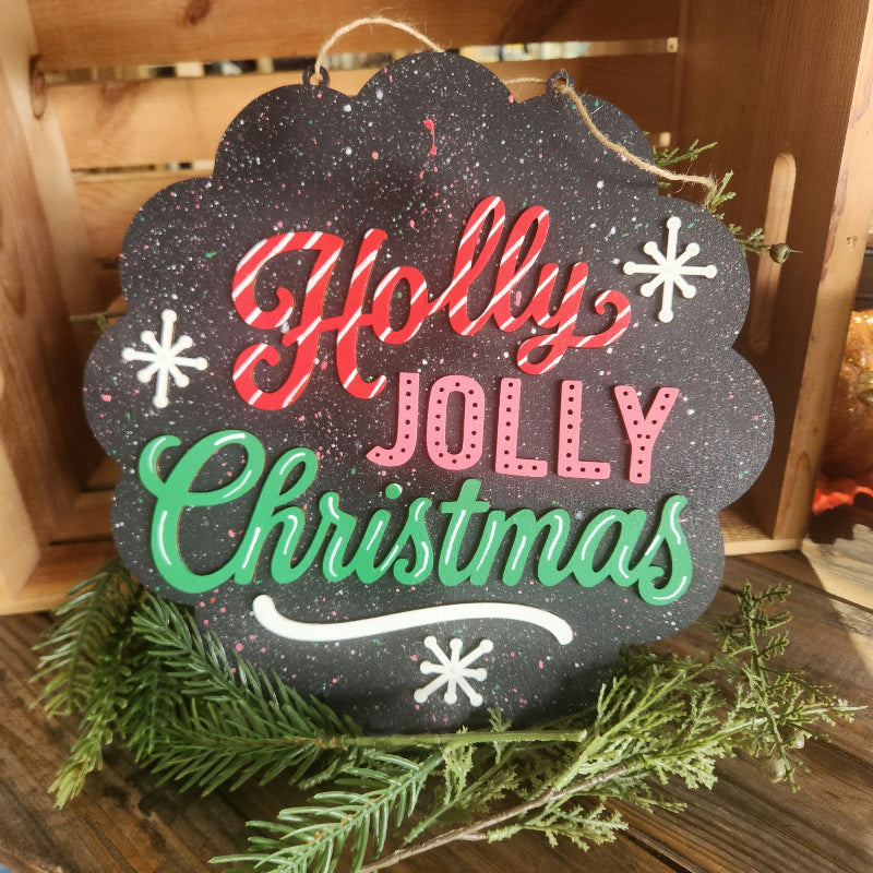 Holly Jolly Christmas layered wooden sign with red candy cane lettering, pink and green accents, white snowflakes and a black paint-splattered background.