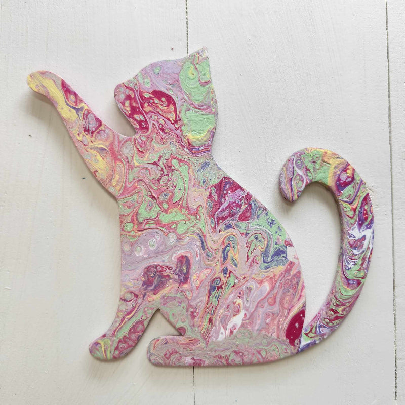 A wooden cutout in the shape of a cat with a paint pour design in multiple colors.