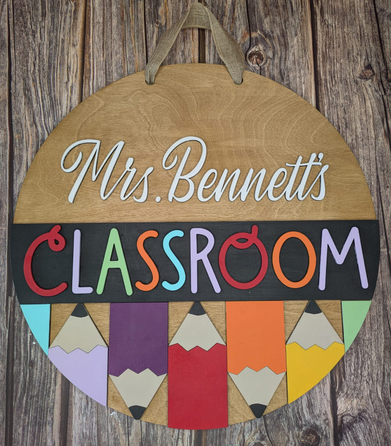 Wooden sign with 'Mrs. Bennett's Classroom' and colorful pencils on a wooden background