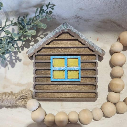Decorative item with wooden slats, beads, and a small window cutout on a textured surface.