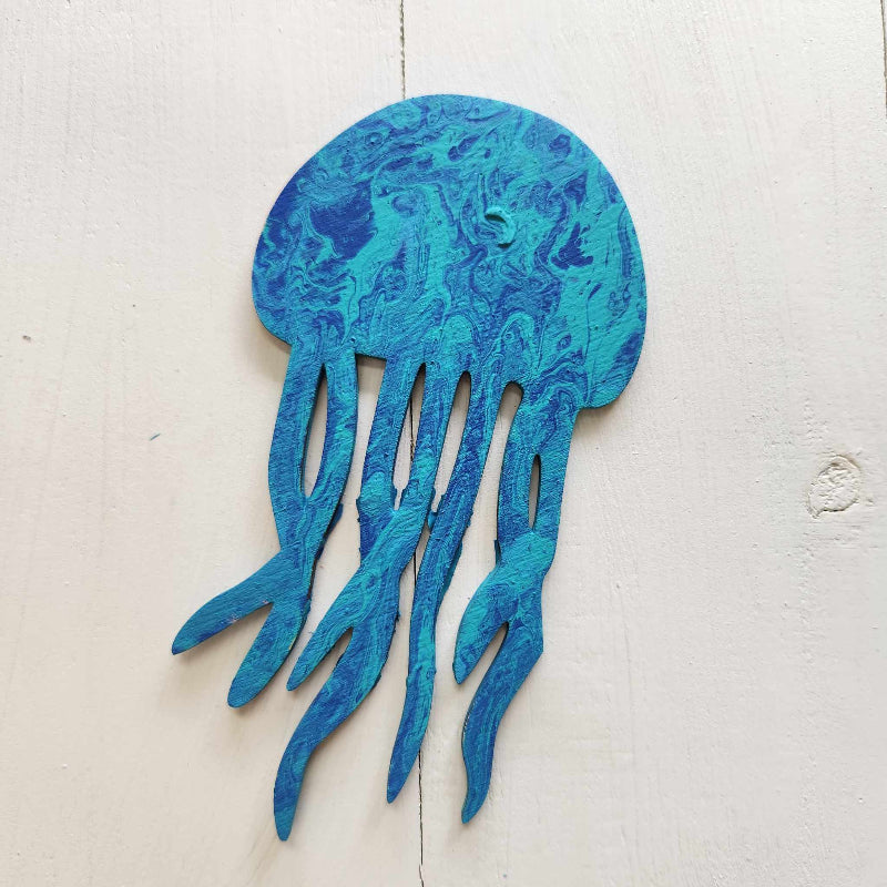 A blue wooden cutout in the shape of a jellyfish with a paint pour design.