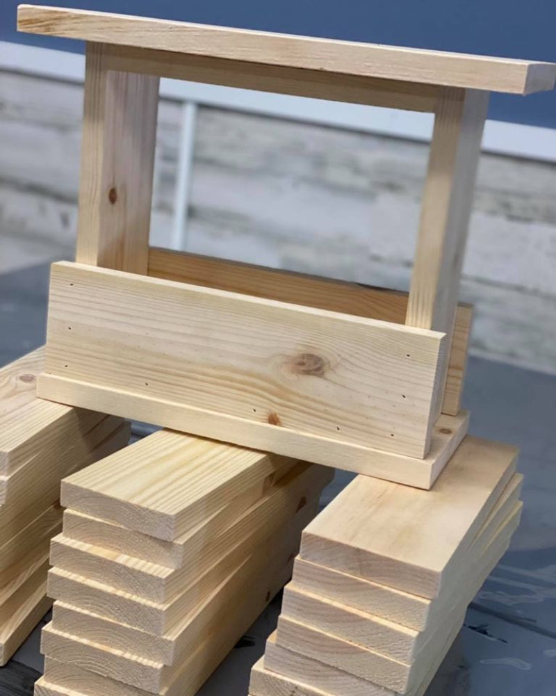 A custom design for a workshop, featuring a pile of unassembled wooden boards and a partially assembled structure with a clear vertical support and a natural wood finish.