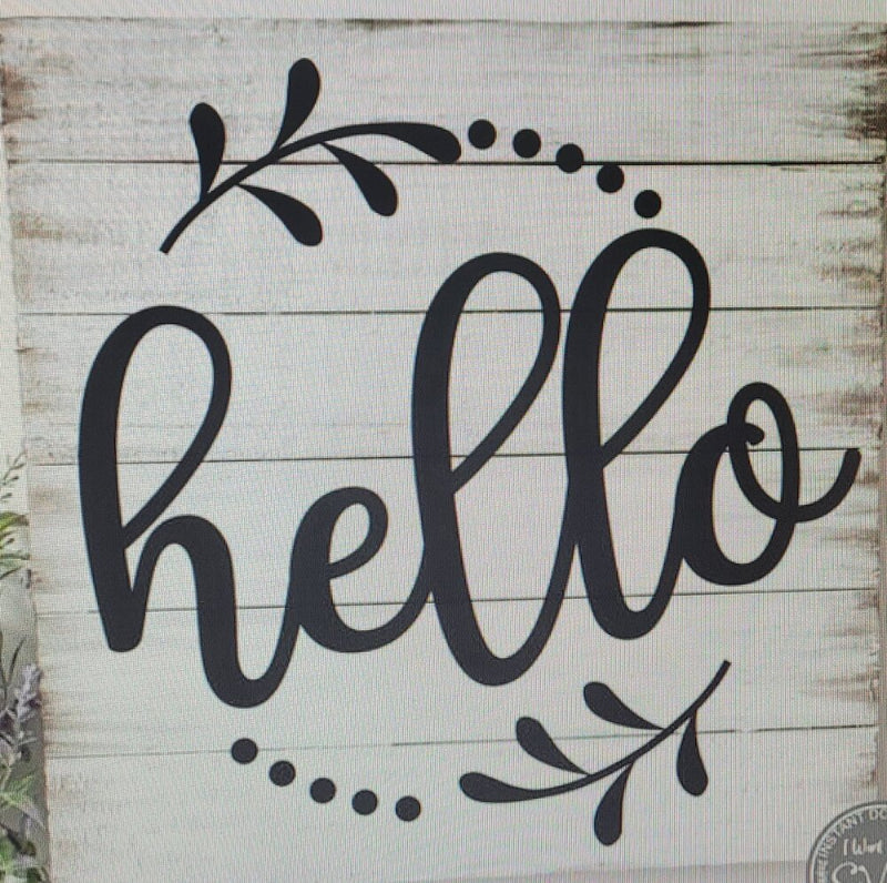 A square decorative plaque with a white wood background and black text that reads 'Hello' surrounded by a leaf pattern.