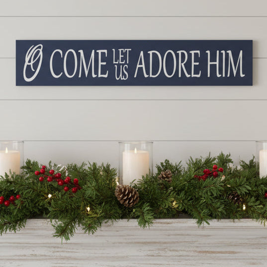 Christmas songs lyrics, O come let us adore Him, written in white letters on a dark blue plank.