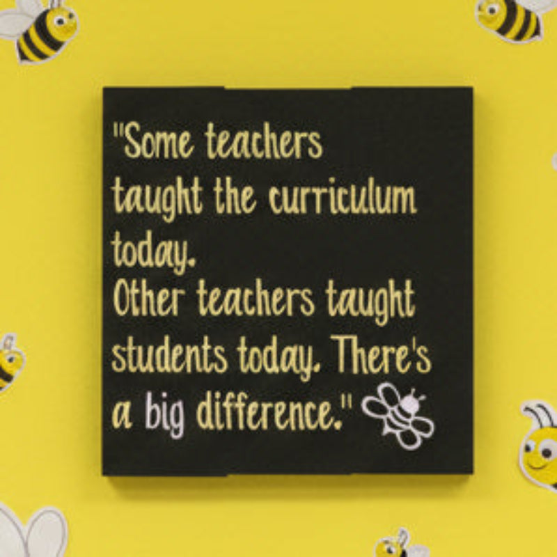 A black square-shaped wall decal with yellow text, featuring a quote about teachers and students, and a small bee graphic.