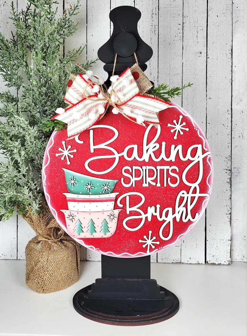 Decorative sign with 'Baking Spirits Bright' text and Christmas-themed design on a stand.