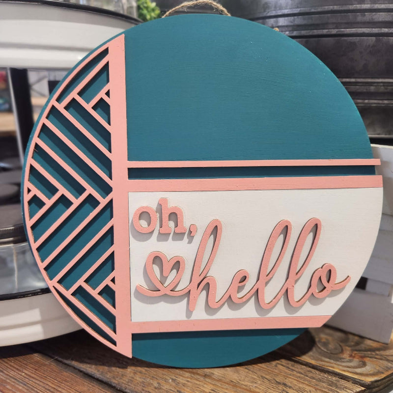 Decorative round sign with 'oh, hello' text on a wooden surface