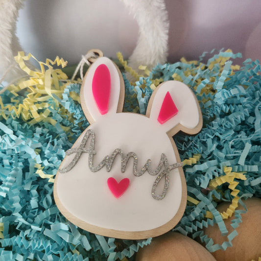 A personalized Easter basket tag in the shape of a bunny with colorful ears and a name written on it.