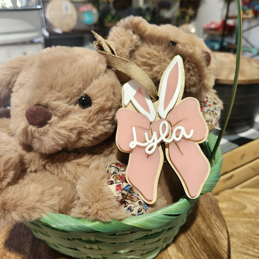 Bunny in a basket with a personalized Easter tag named 'Lyla' on an acrylic and wood surface