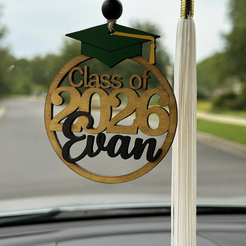 Graduation-themed ornament with 'Class of 2026 Evan' on a car window.