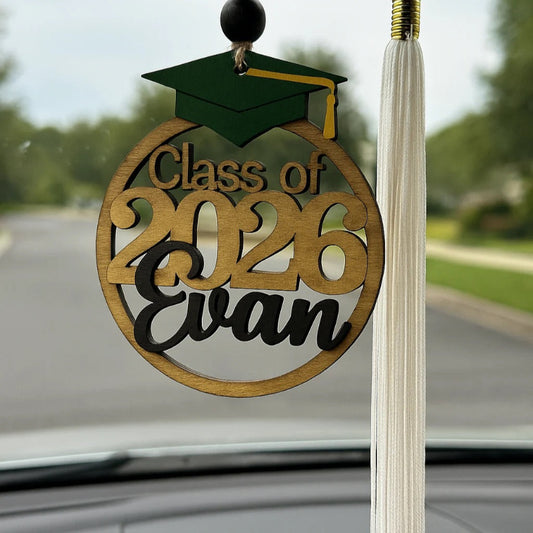Graduation-themed ornament with 'Class of 2026 Evan' on a car window.