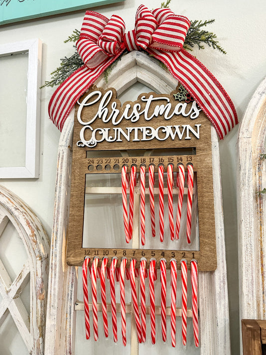 Christmas countdown calendar with candy canes and a large red and white bow on a decorative wall.