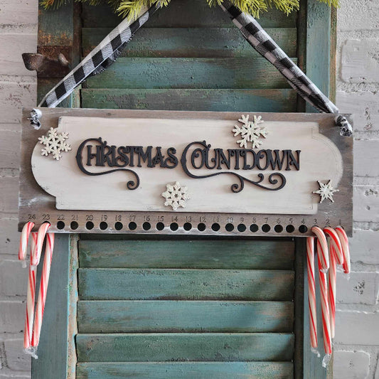 A 3D plank sign with 'Christmas Countdown' text and decorative snowflake patterns, mounted on a door with candy canes hanging from it.