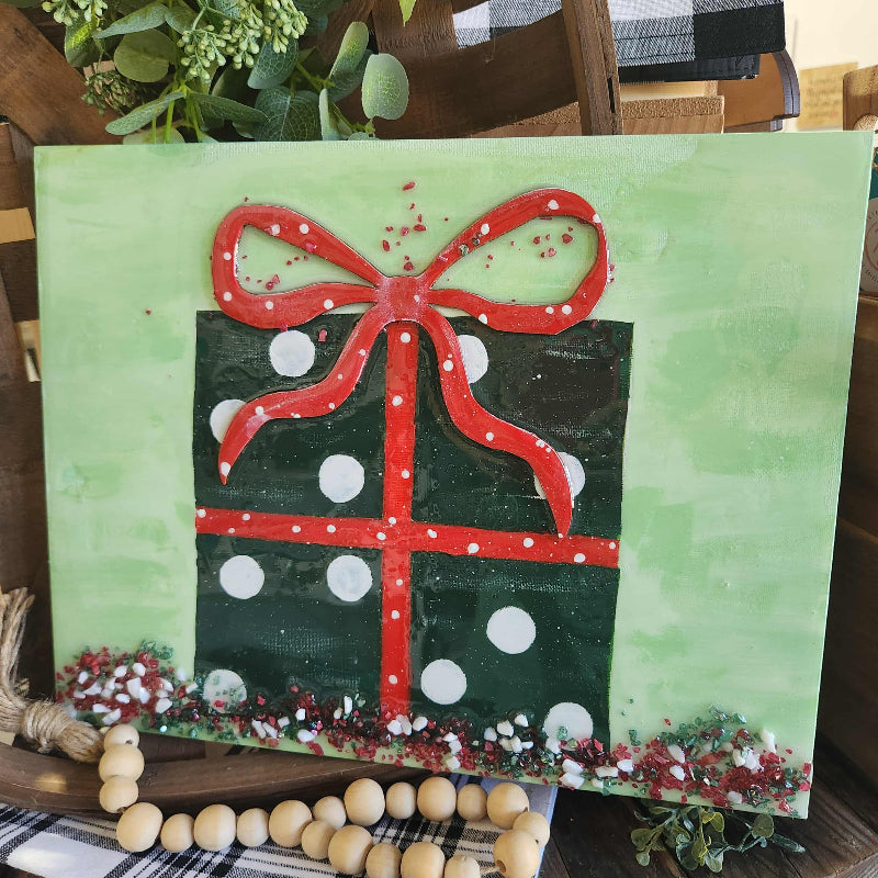Painting of a green present with a red bow on a green background with crushed glass and epoxy