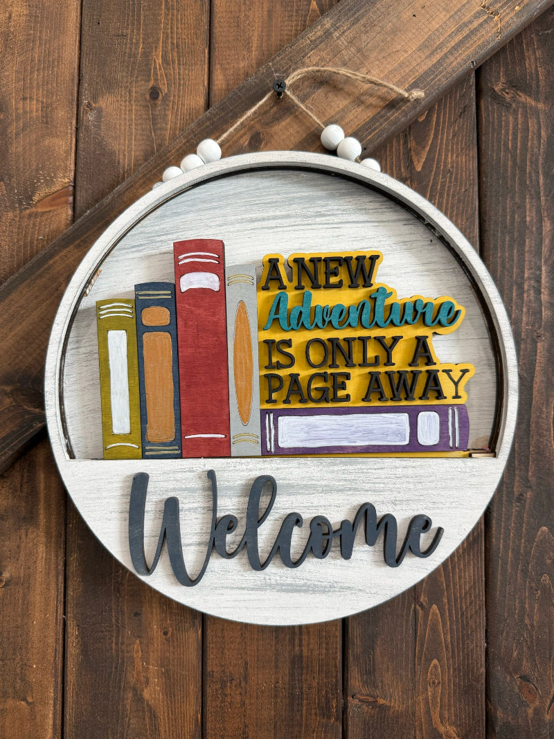 Decorative sign with books and 'Welcome' text on a wooden background