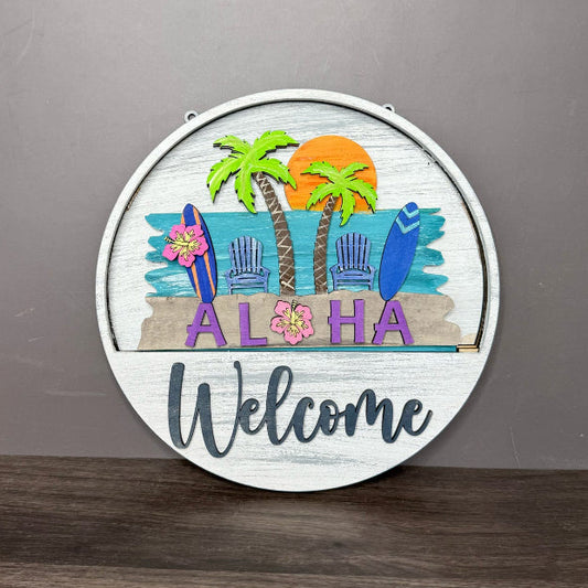 Decorative sign with tropical design and 'Aloha Welcome' text on a wooden surface.