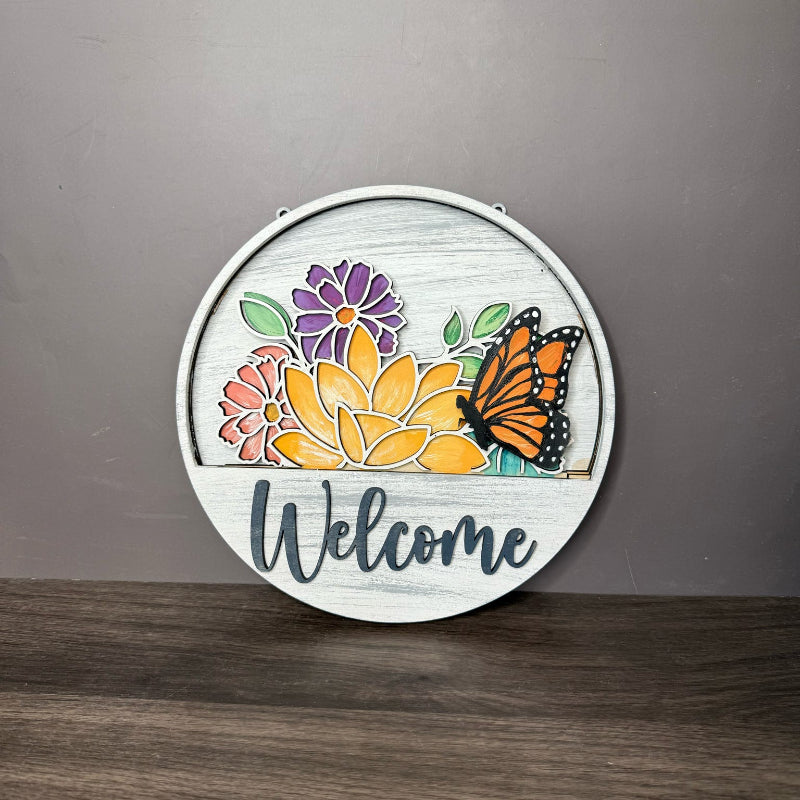 Decorative round sign with flowers and a butterfly on a wooden surface and gray background