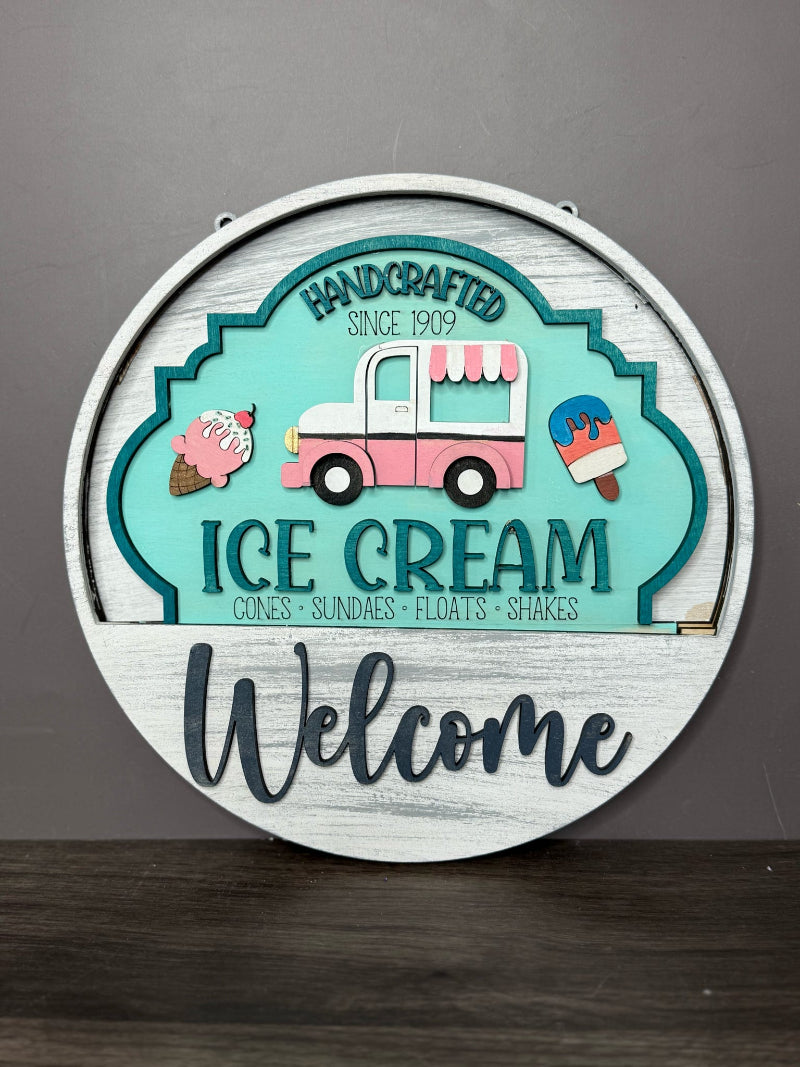 Decorative sign with ice cream truck design and 'Welcome' text on a gray background