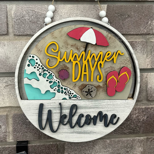 Decorative sign with 'Summer Days Welcome' text, beach umbrella, flip-flops, and wave design on a stone wall background.