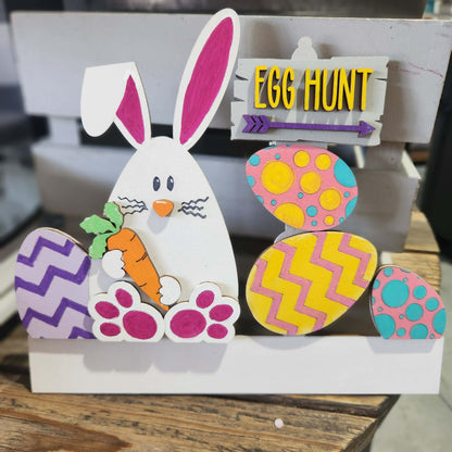 Colorful Easter decoration with a bunny and eggs on a wooden surface.