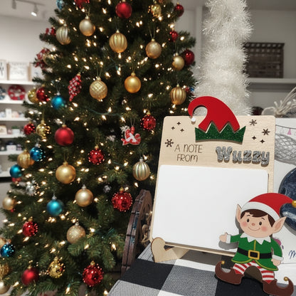 Wooden Christmas card with red and green design and text 'A Note From' on a blurred background.