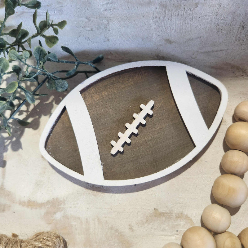 Wooden football ornament on a textured surface with decorative elements