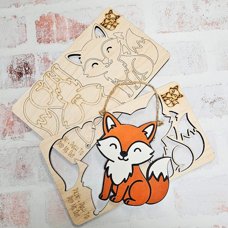 Wooden fox cutout with a hanging string on a textured white surface