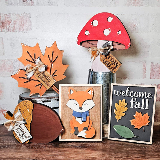 Decorative items with autumn theme including a fox, leaves, and mushroom on a wooden surface.