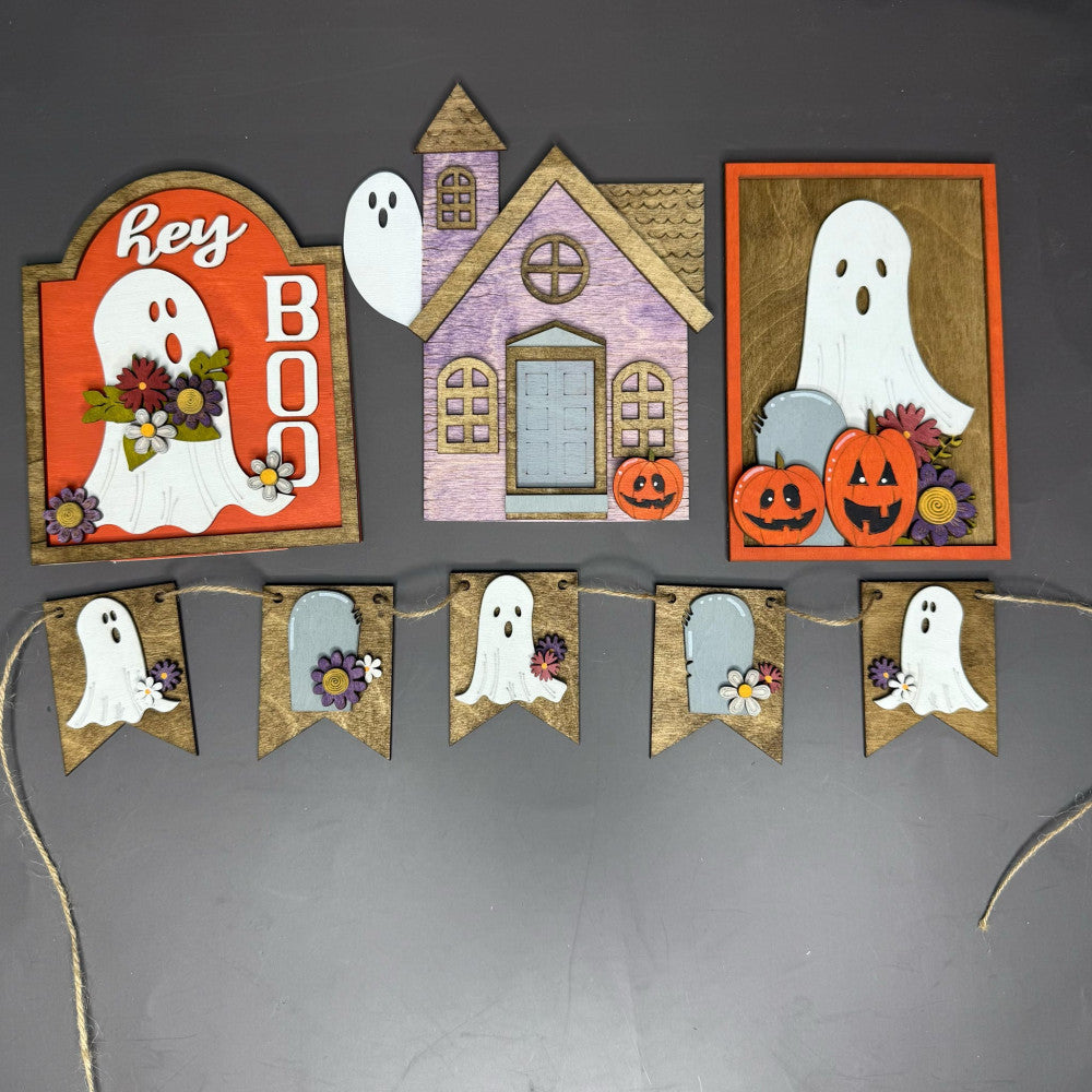 Halloween-themed decorative items including signs with ghosts and pumpkins, a small house, and a banner on a dark background.