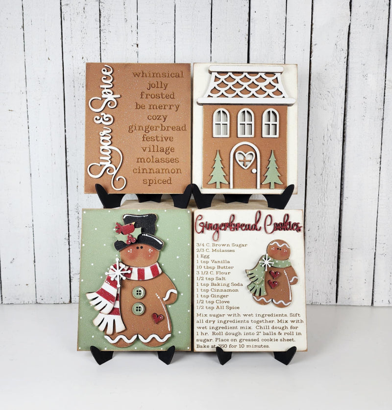 Decorative gingerbread-themed signs on a white surface with a wooden background.