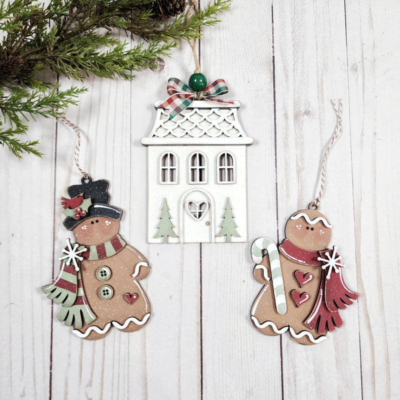 Decorative Christmas ornaments on a wooden surface with a white house ornament.