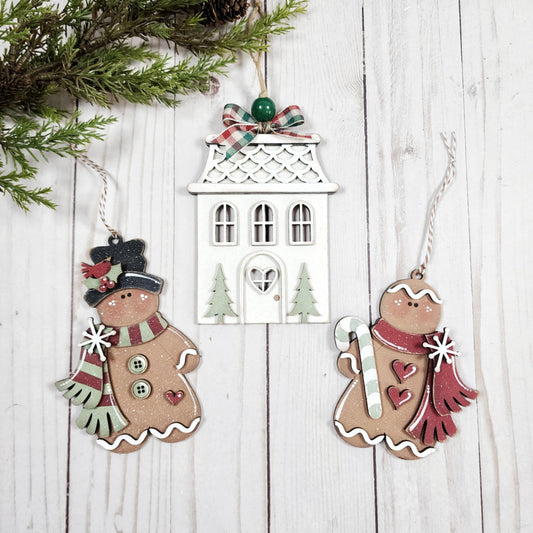 Decorative Christmas ornaments on a wooden surface with a white house ornament.
