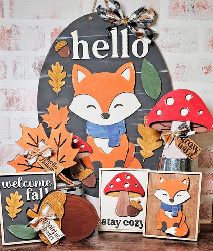 Decorative sign with fox and mushroom designs, featuring autumnal elements and text.