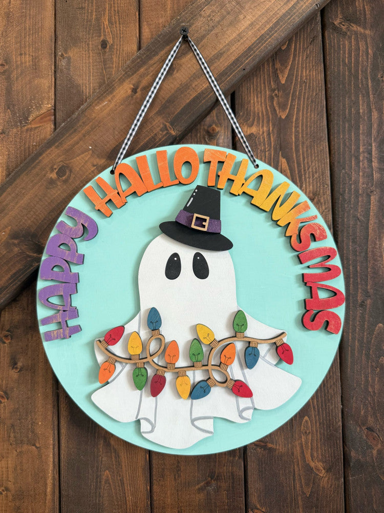 Decorative sign with ghost, witch hat, and Christmas lights on a wooden background