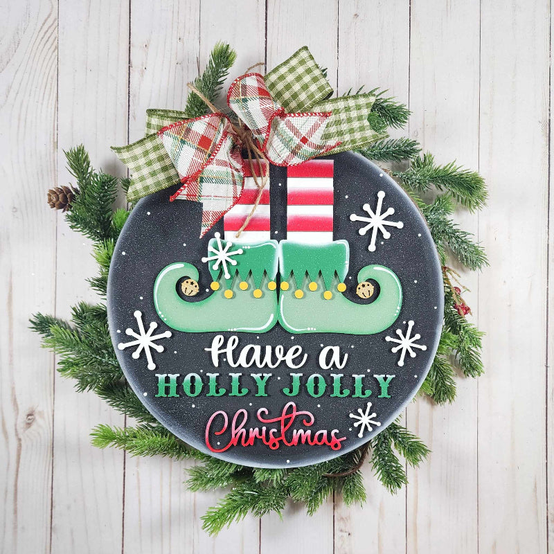 Decorative Christmas sign with elf shoes, presents, and 'Holly Jolly Christmas' text on a wooden background.