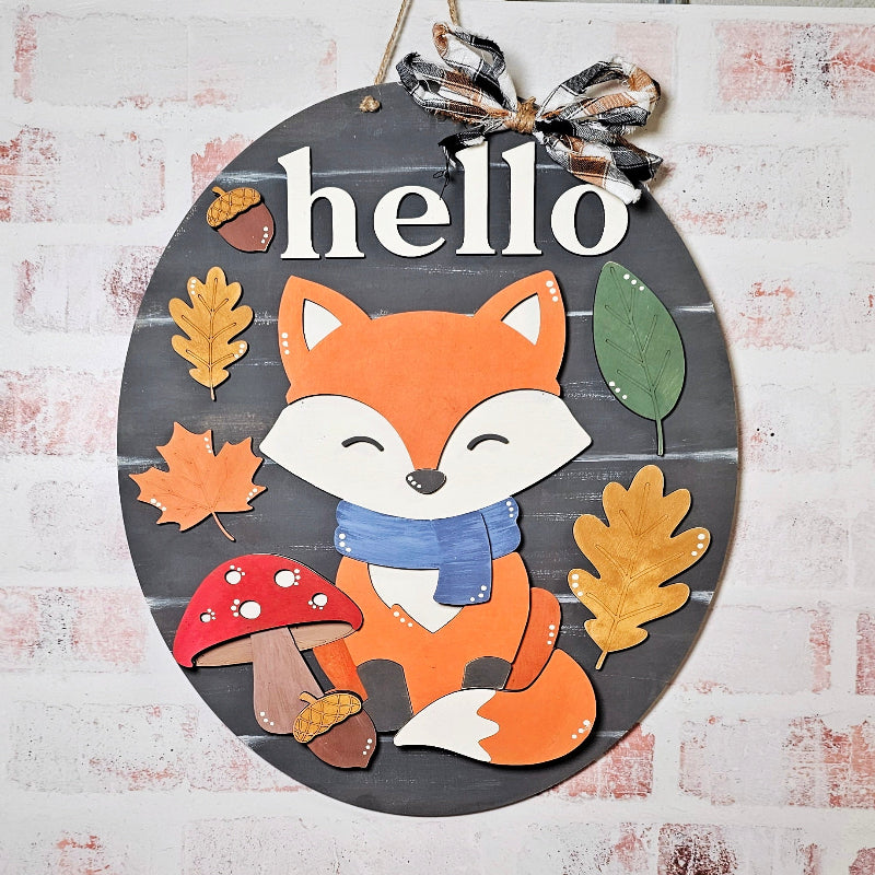 Decorative sign with a fox illustration and 'hello' text on a wooden background