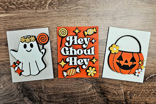Three Halloween-themed cards on a wooden surface.