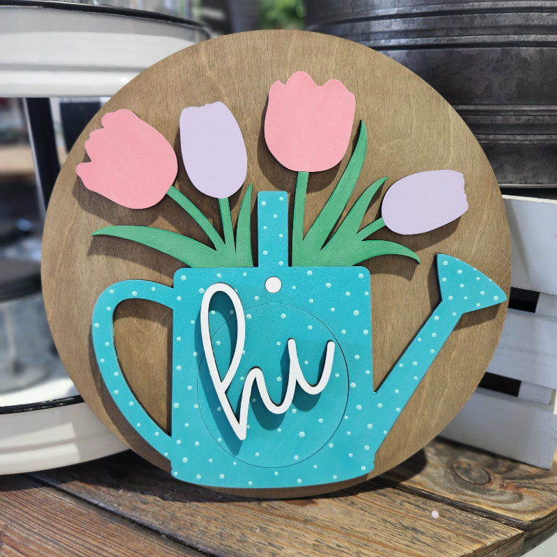 Decorative wall art with a watering can and tulips on a wooden background