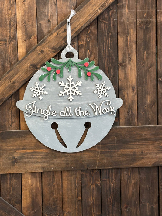 Decorative Christmas bell sign with 'Jingle all the Way' text on a wooden background