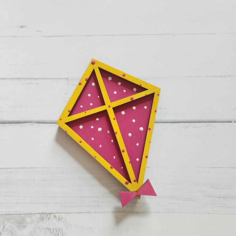 Pink and yellow kite-shaped wall decor on a light wooden surface