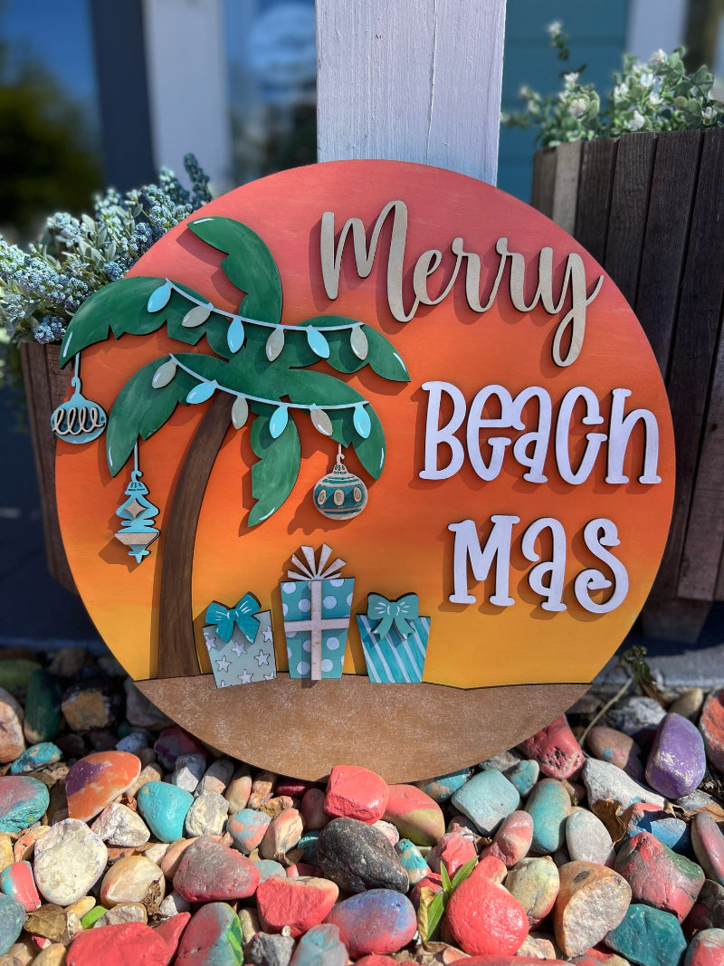 Decorative sign with 'Merry Beach Mas' text, palm tree, and presents on a colorful stone background.