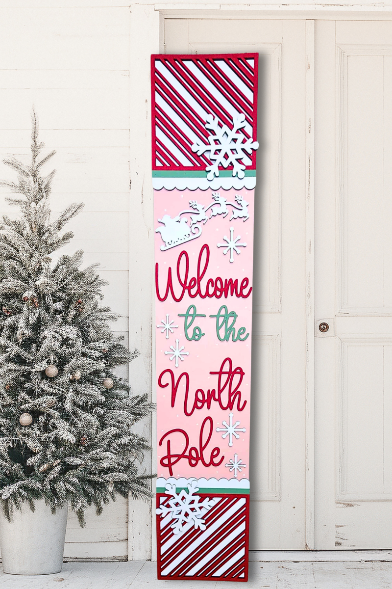 Decorative sign with 'Welcome to the North Pole' text next to a Christmas tree.