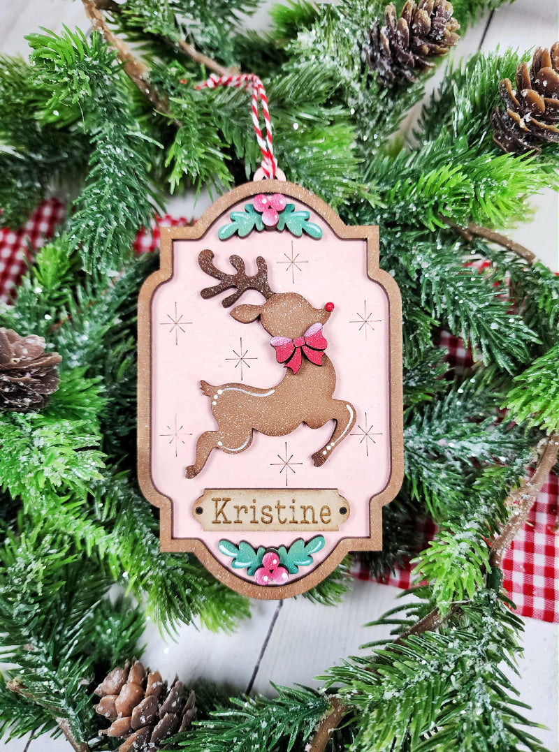 Decorative Christmas ornament with a reindeer design and 'namr' text, hanging on a Christmas tree.