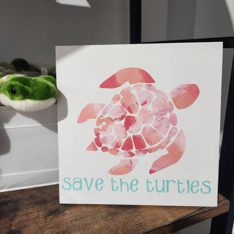 Card with a turtle illustration and 'save the turtles' text on a wooden surface.