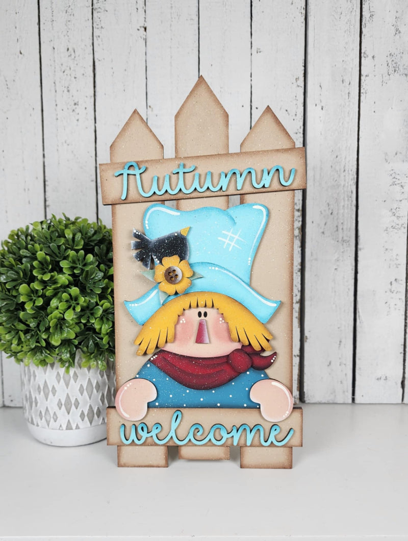 Scarecrow leaning on a wooden fence background