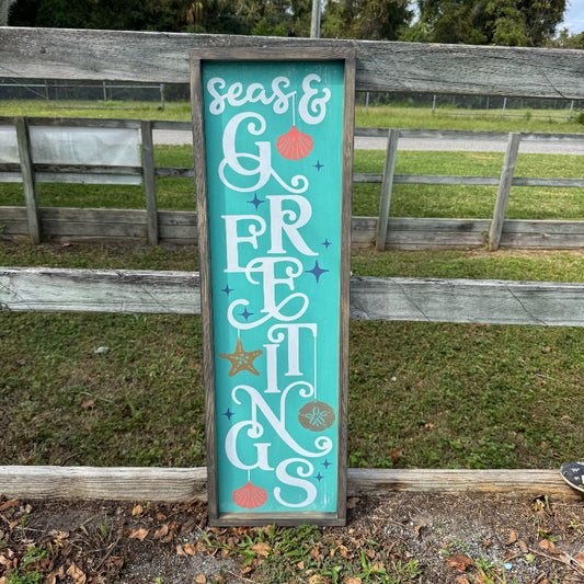 Decorative sign with 'Seas & Gretings' text in a rustic outdoor setting